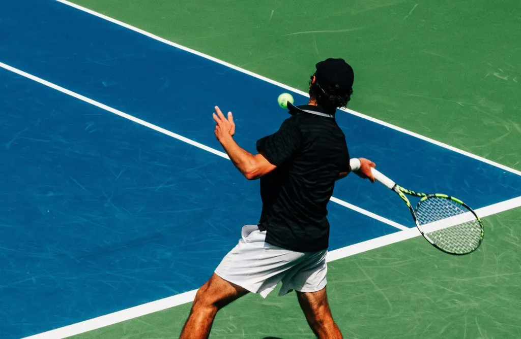 Joueur de tennis vu de dos frappant une balle