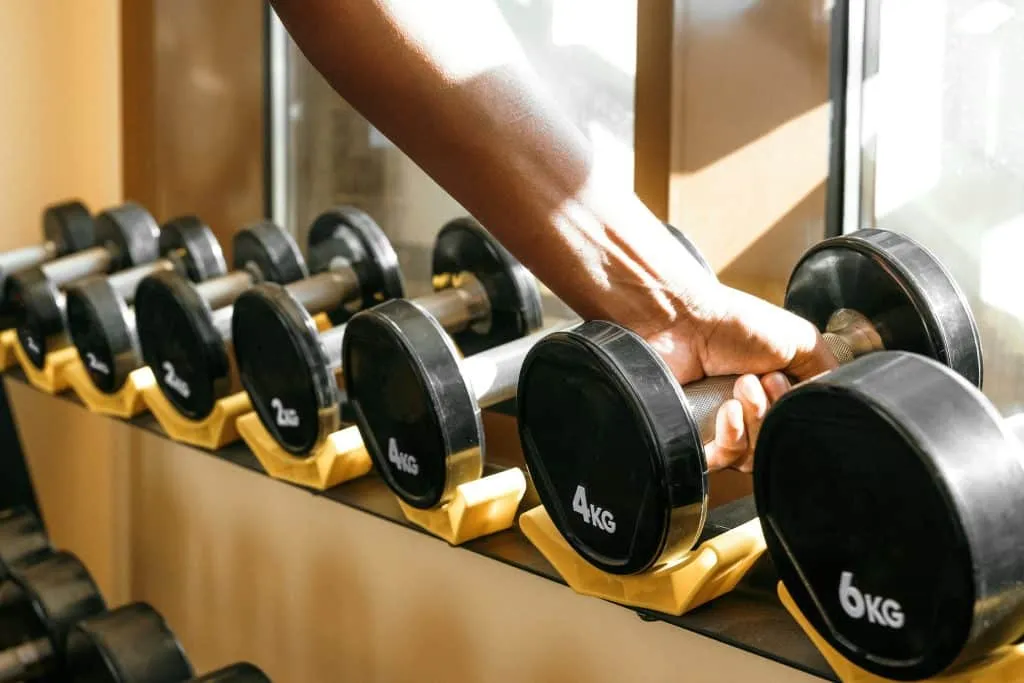 Main saisissant un haltère sur un rack de musculation