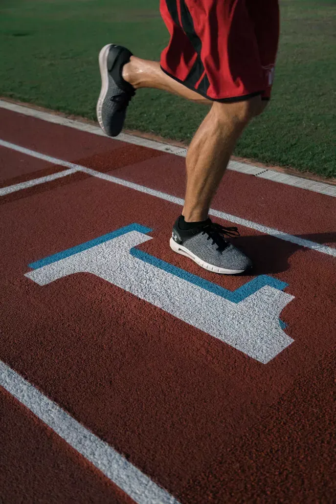 Jambes d’une personne qui court sur une piste, en illustration des questions à poser avant la reprise après une blessure musculaire