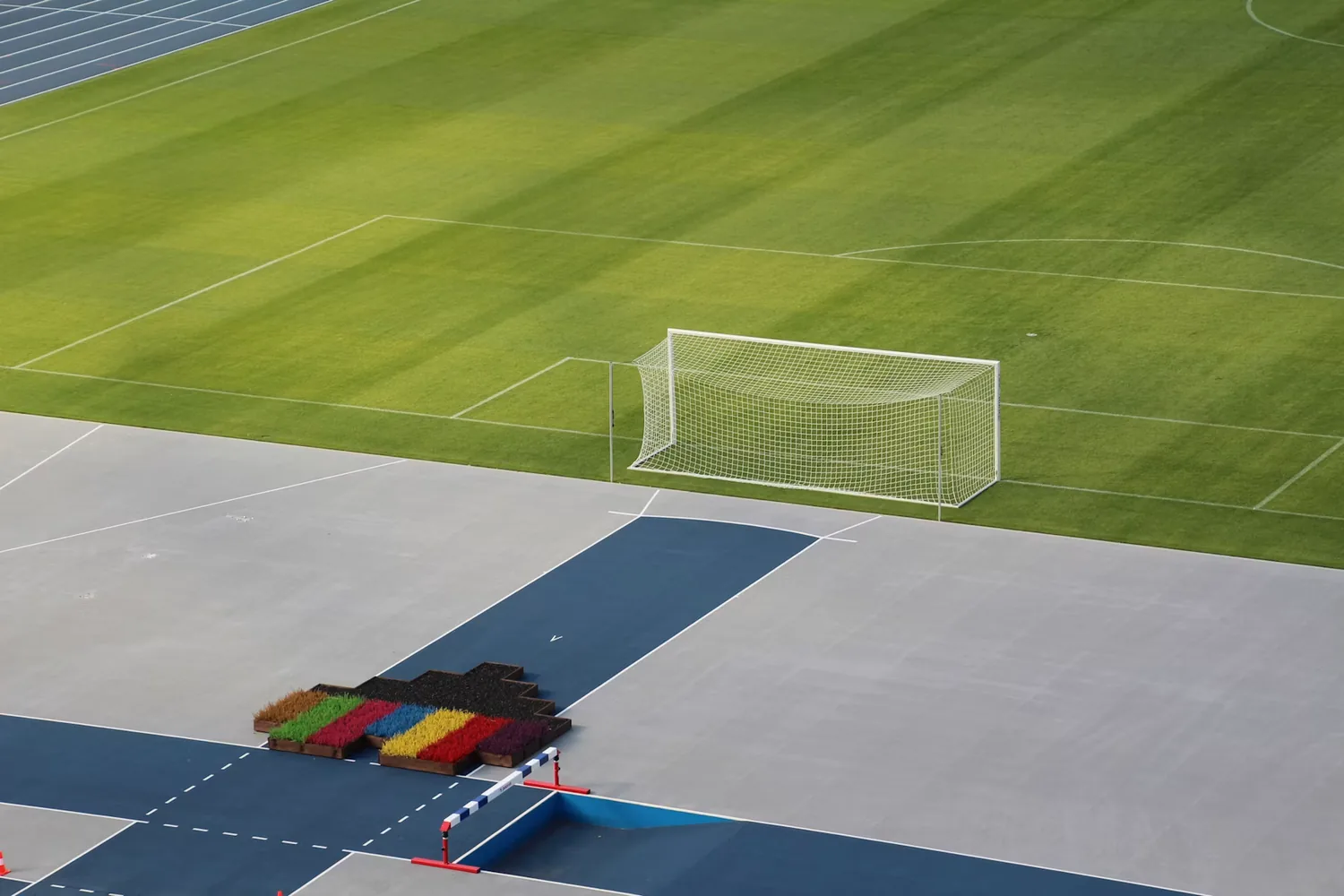 Terrain de football et piste d’athlétisme vides, illustrant les sports à reprendre après une rééducation du genou